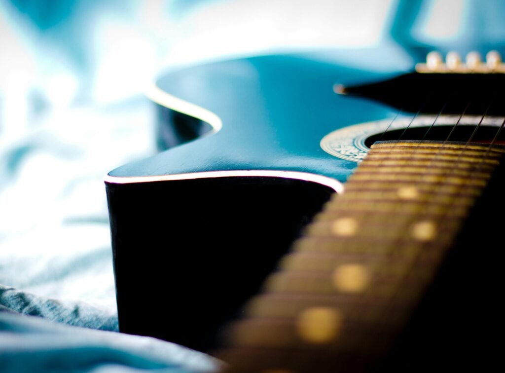 Artistic close-up of a blue acoustic guitar resting on a blurred fabric background.